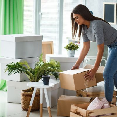 Image shows a woman placing a box down amongst other packing boxes